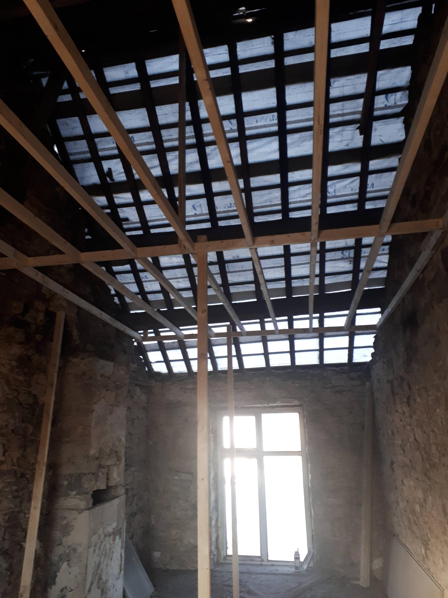Exposed stonework and roof structure during strip out